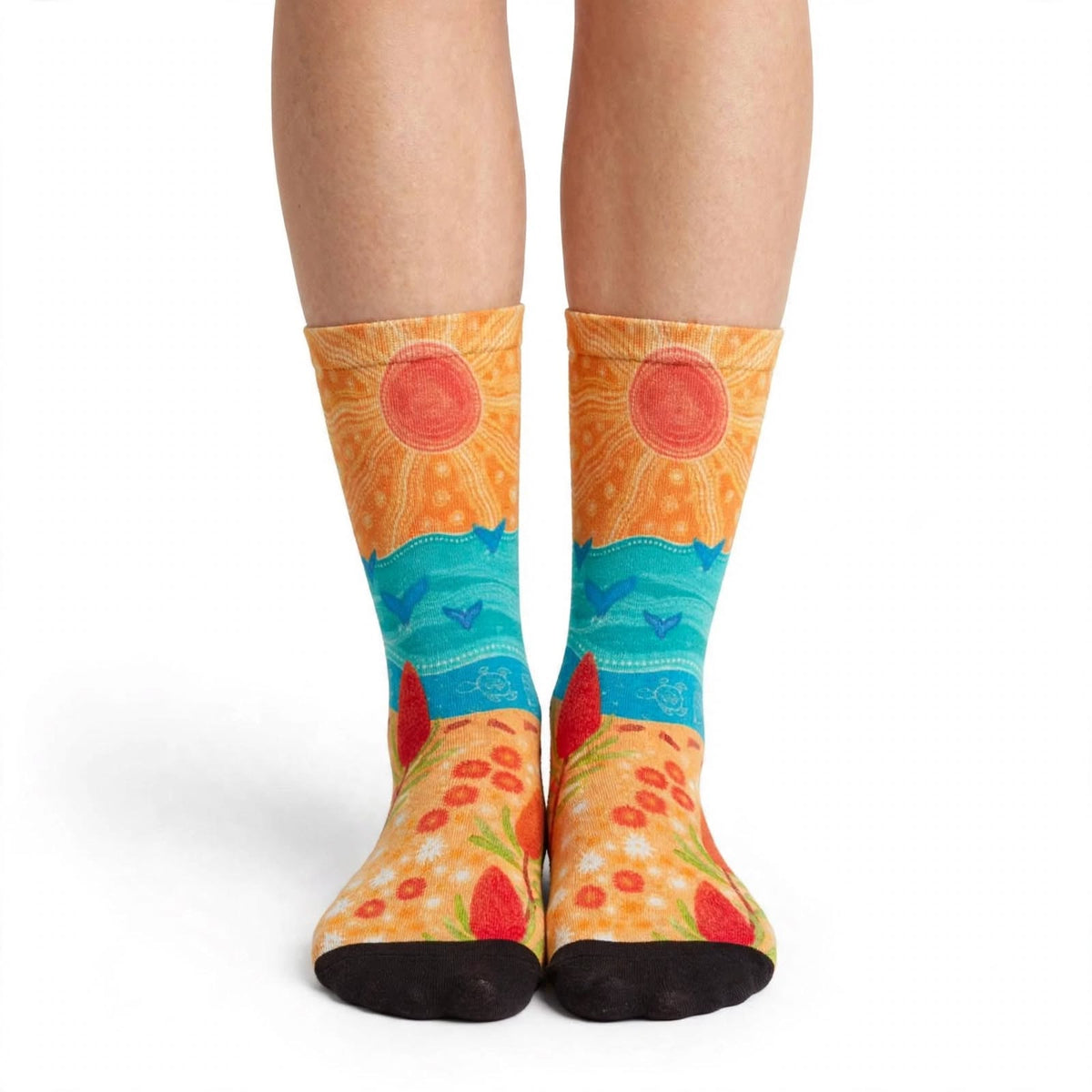 Coastal Gathering by Caitlin Trindall: orange and turquoise bamboo socks with sun motifs and coastal patterns worn on feet, front view.