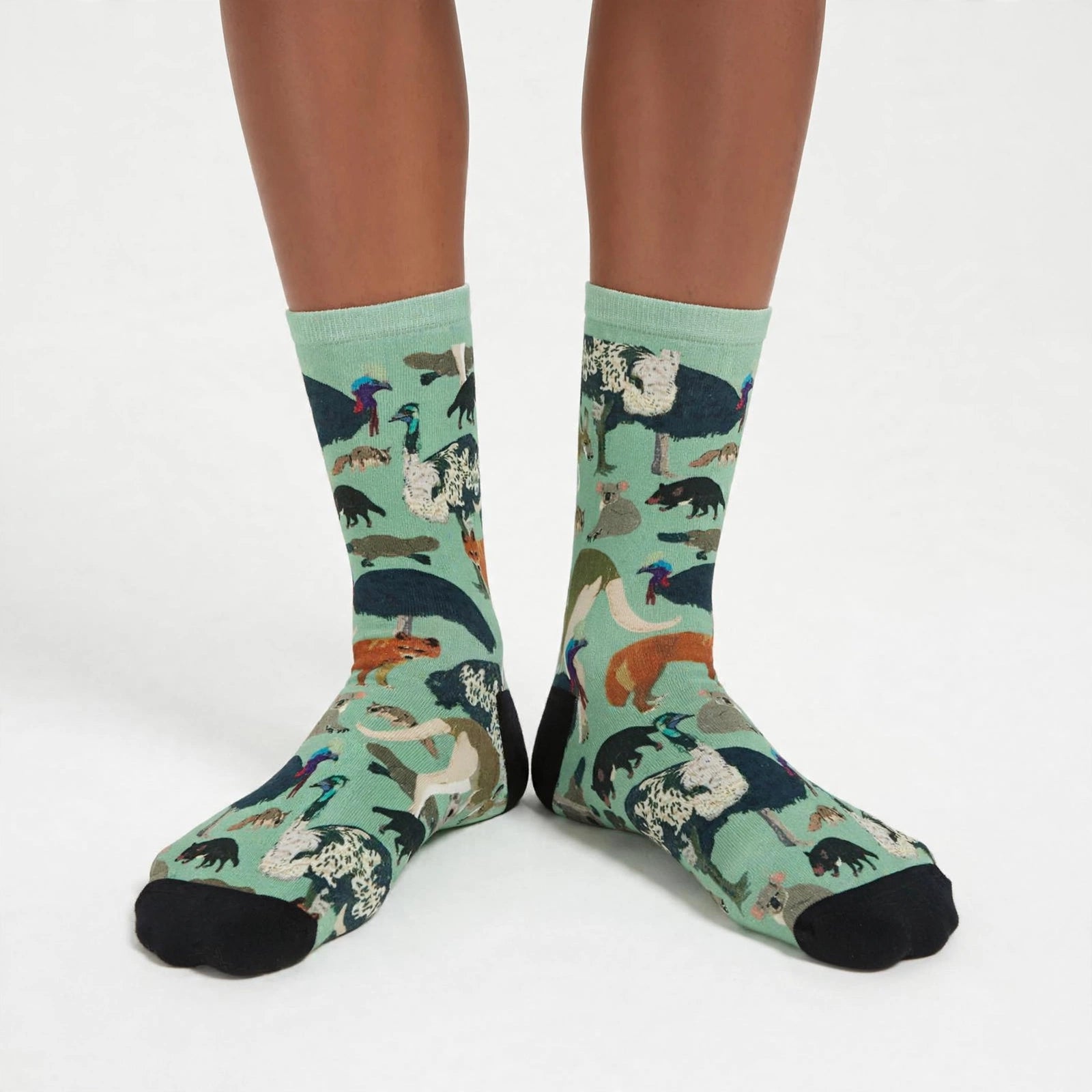 Mint-green Australian wildlife socks featuring kangaroos, wallabies, koalas, wombats, Tasmanian devils, dingoes, numbats, platypuses, echidnas, cassowaries and emus, with black toes and heel