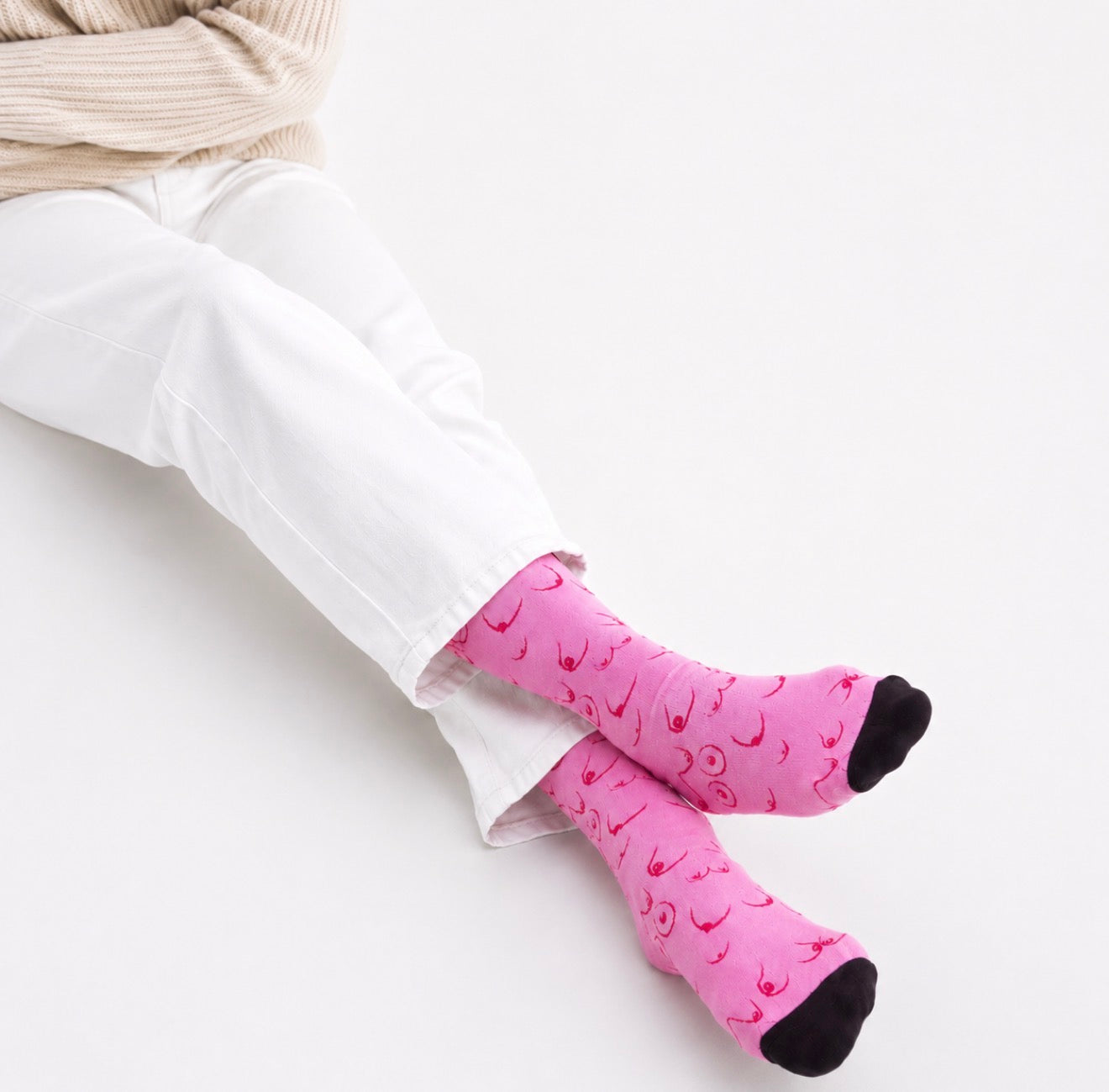 Pink novelty socks featuring an all-over breast illustration pattern with black toe and heel accents. Fun body positive socks for women and unique gift ideas.