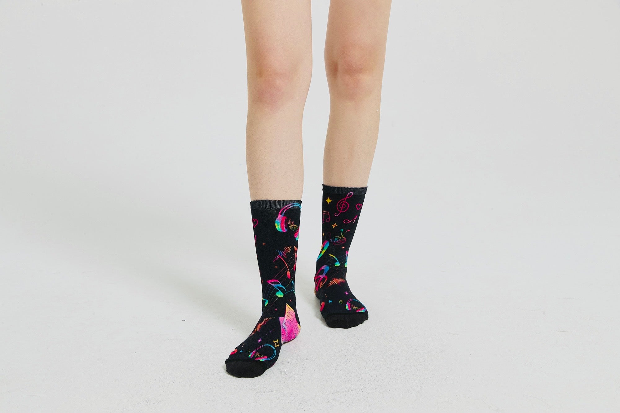 Colourful bamboo socks featuring rainbow music notes and headphones on a black background.
