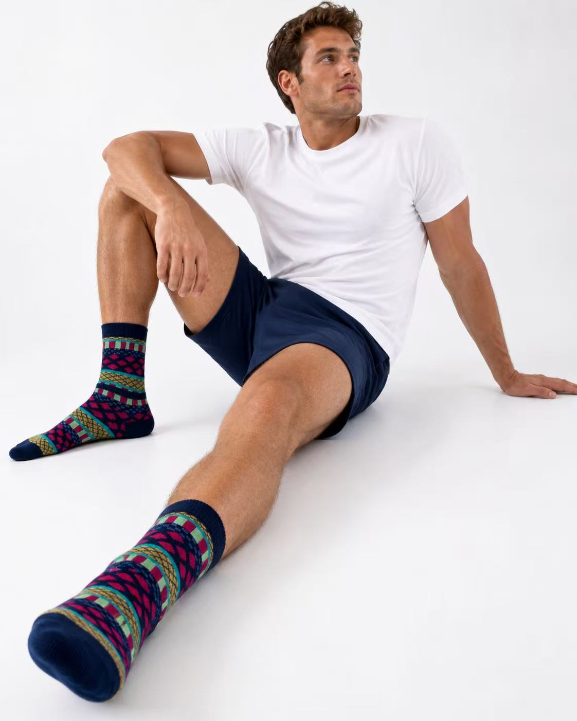 Man wearing patterned socks and dark shorts sitting on a white surface