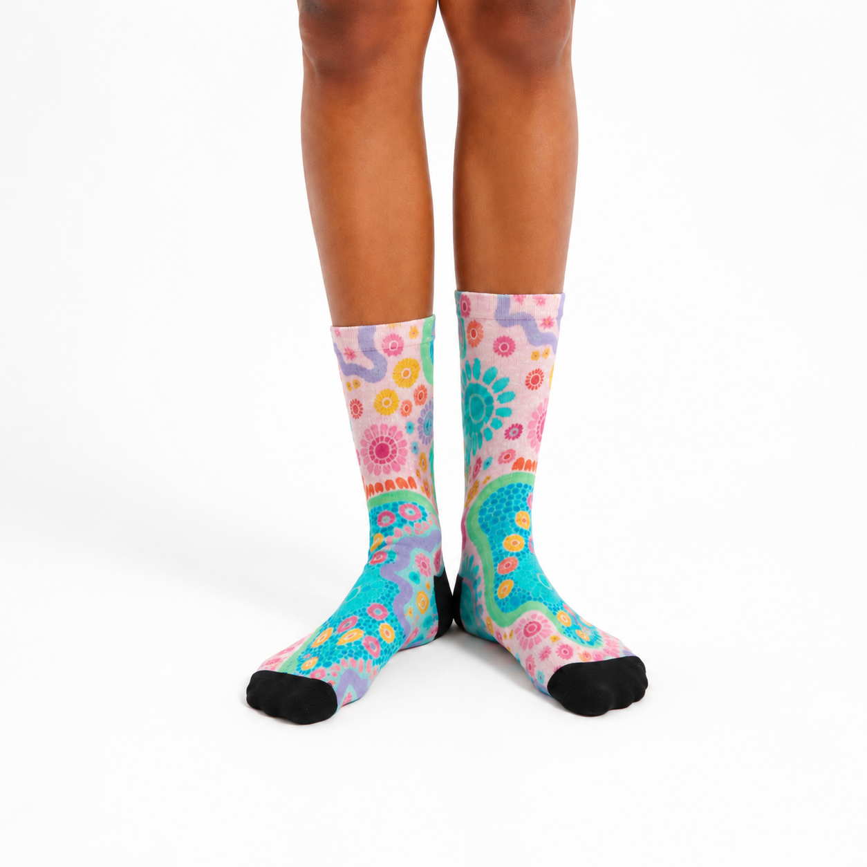 Colorful patterned socks worn by a person on a white background. aboriginal designs by Caitlin_Trindall