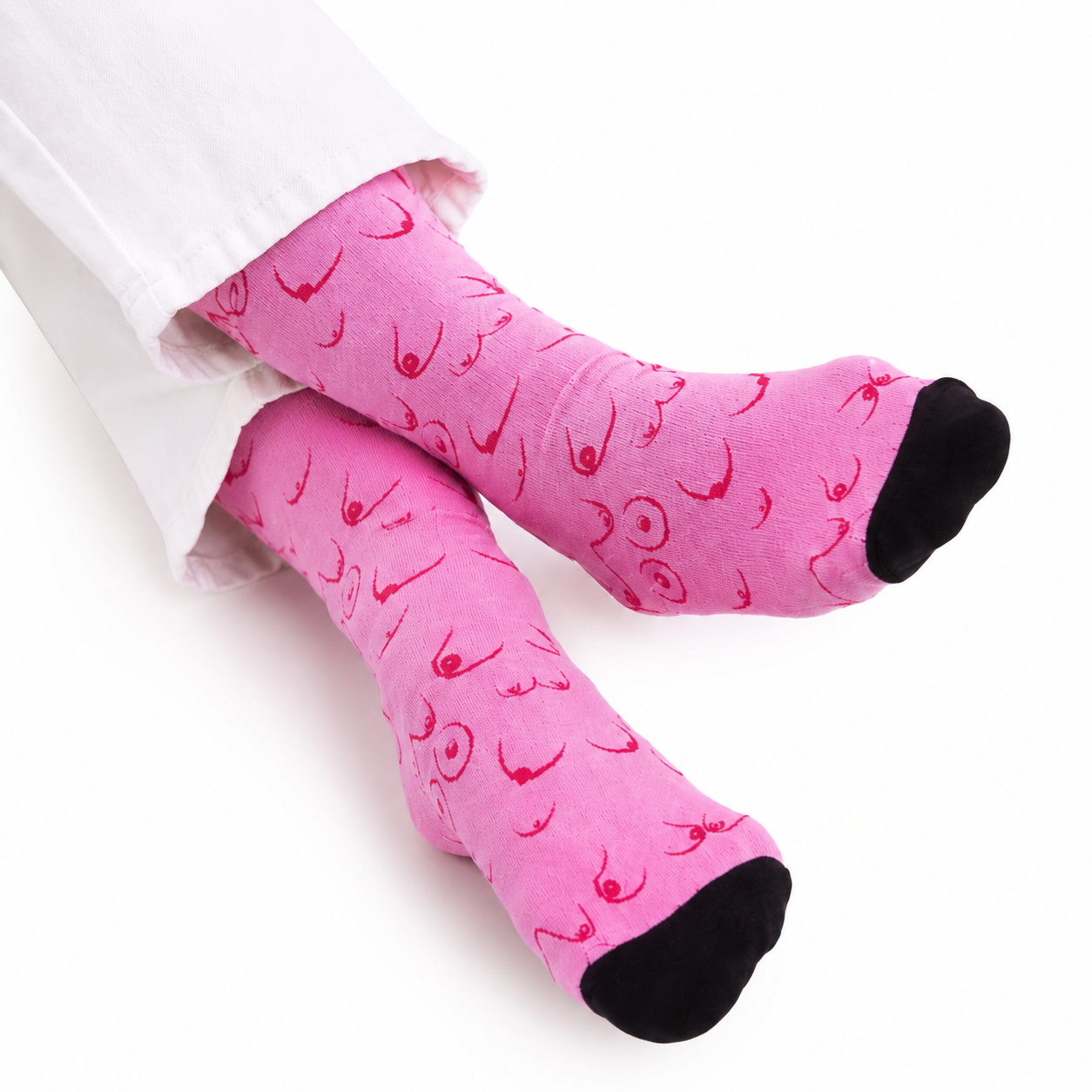 Pink novelty socks with a red graphic print of stylized female boobs, worn with white pants on a white background.