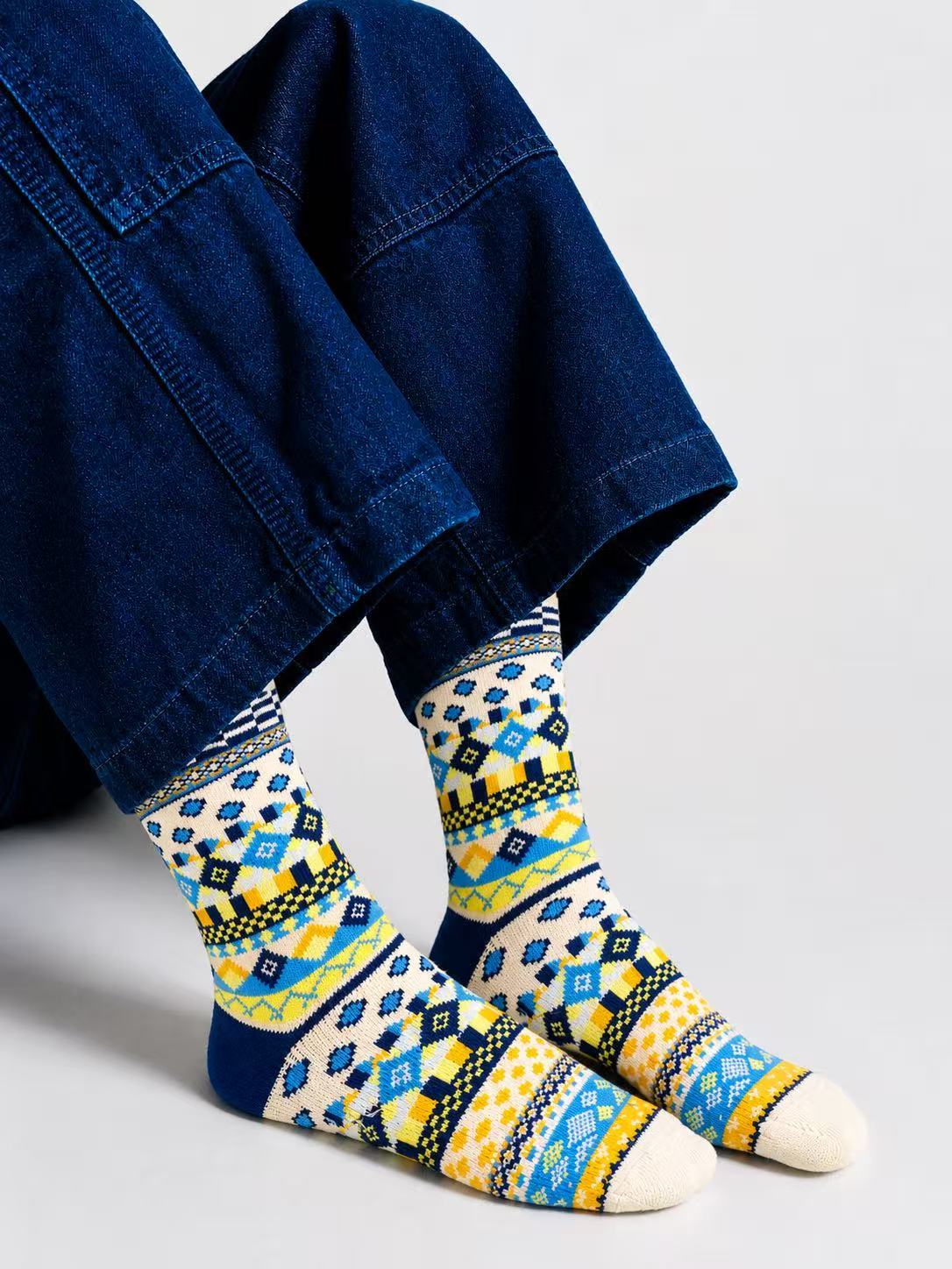 Person wearing patterned socks with a blue jacket on a light gray background
