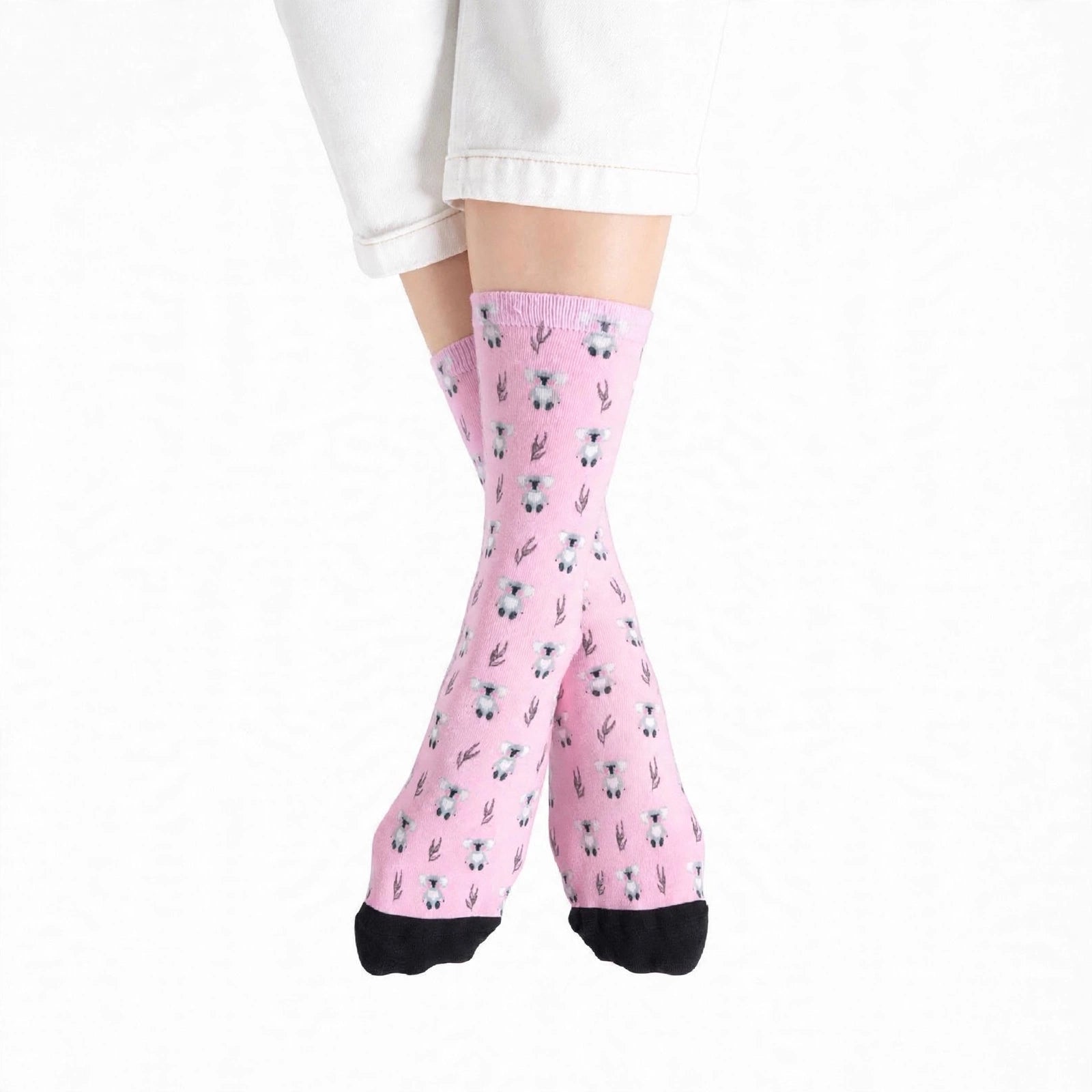 Pink crew socks with a small koala print and black toes, worn on a person's legs with white pants visible at the top.