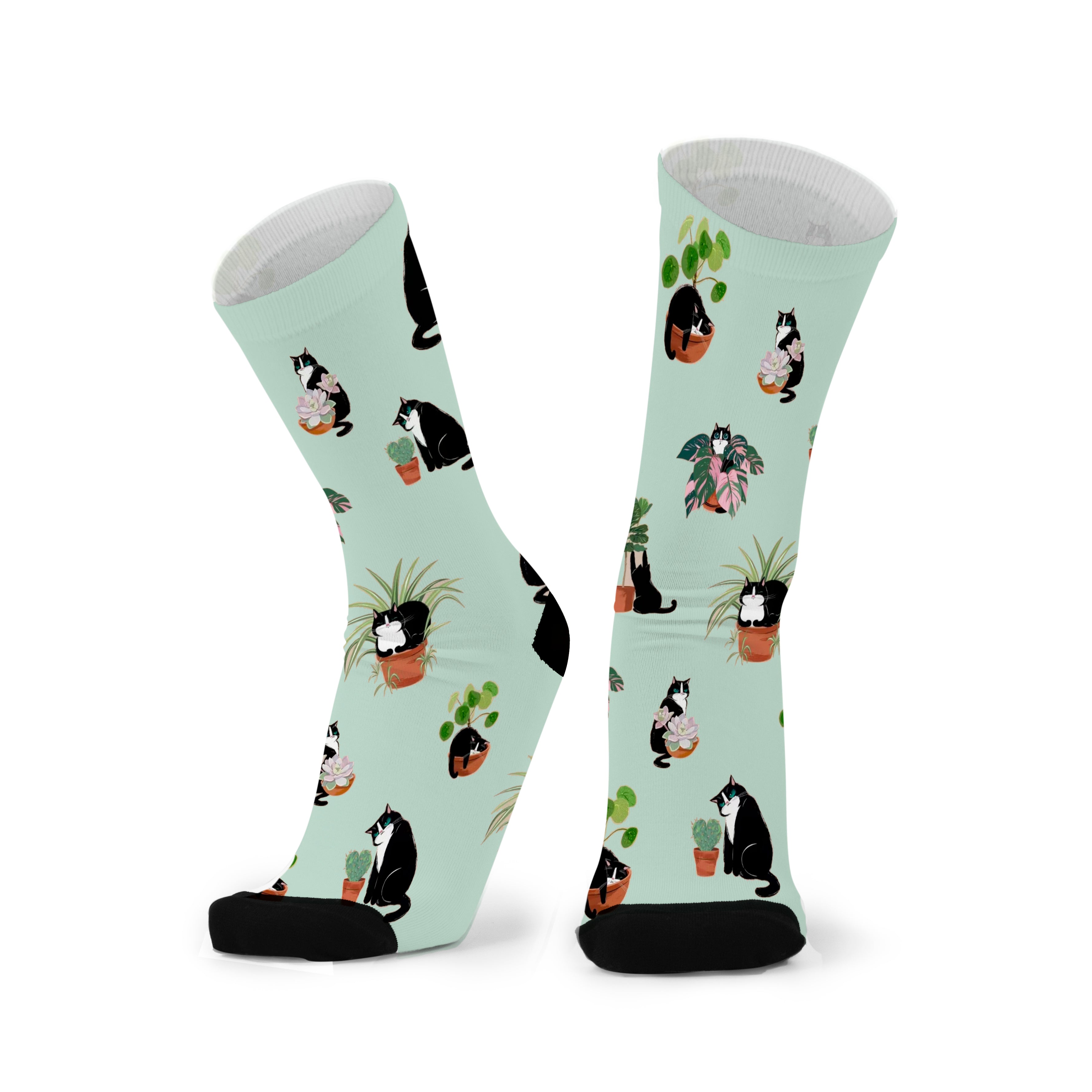Colourful bamboo socks featuring cats and plants on a light green background.