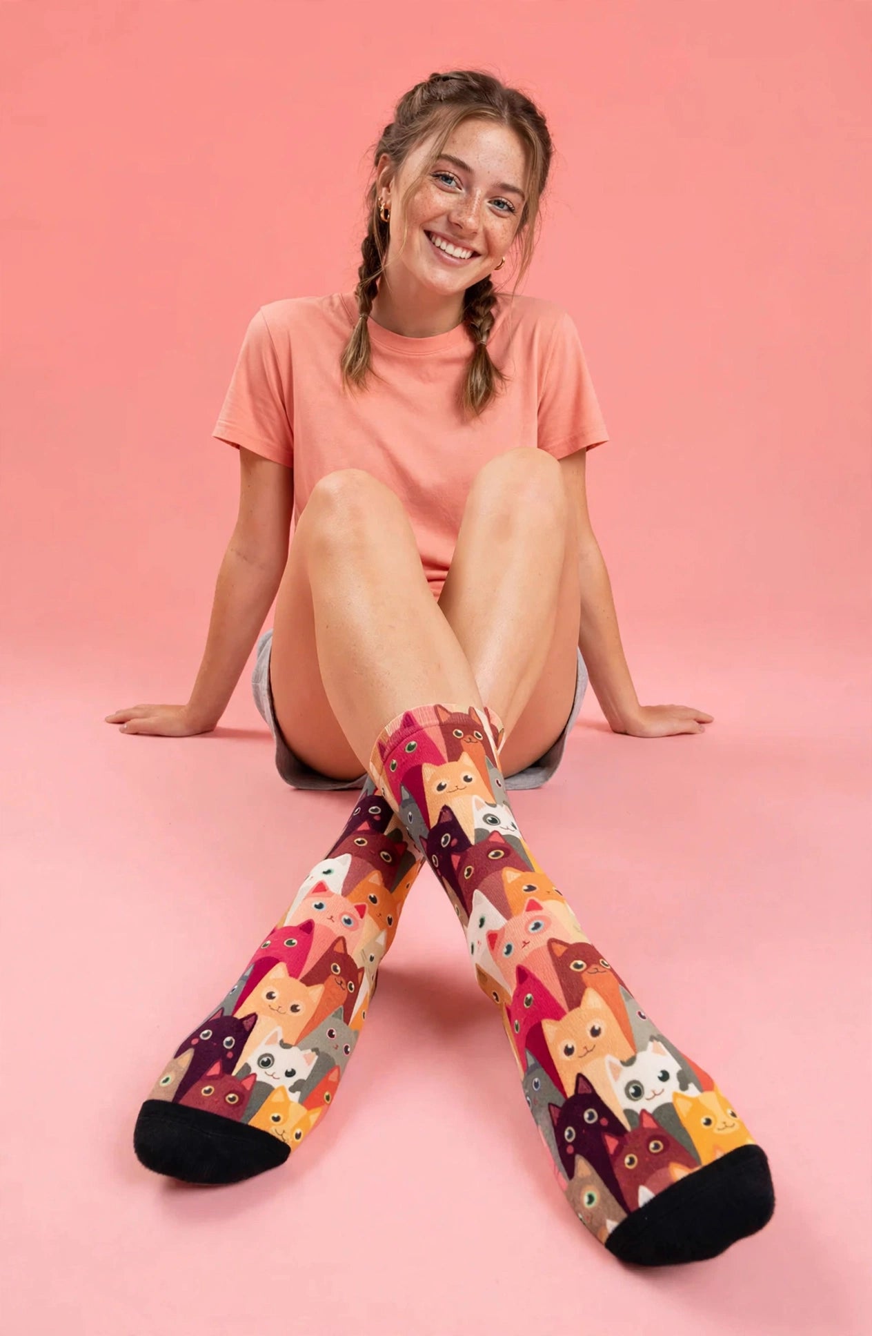 Colourful Herding Cats socks featuring rows of playful illustrated cats in pink, orange, red, grey, cream and brown.