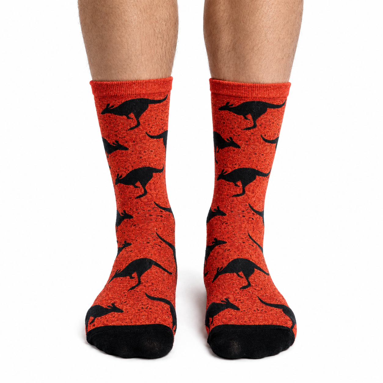 A pair of crew socks worn on a person's feet, featuring a bright orange-red background with a black kangaroo pattern and black toe/heel sections, shown against a plain white background.