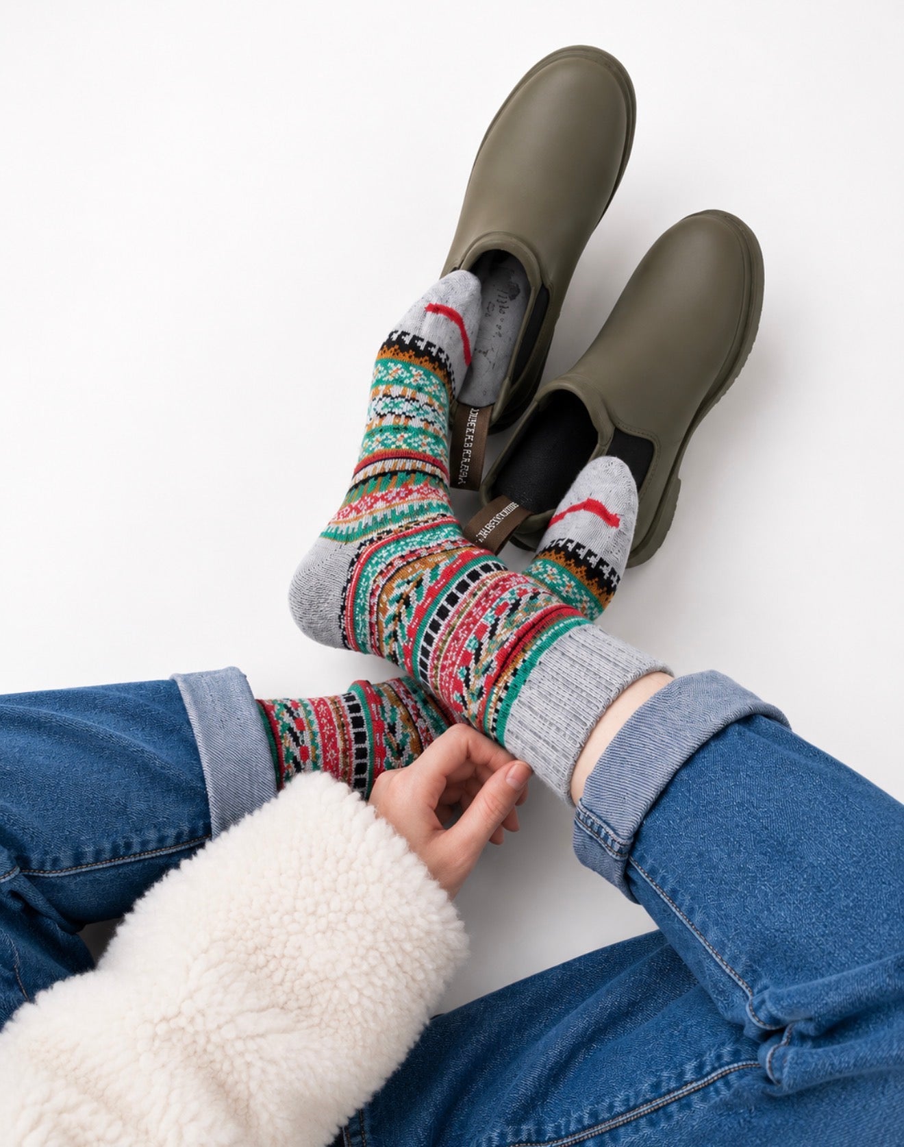 Person wearing green shoes and colorful patterned Nordic style cotton socks on a white background