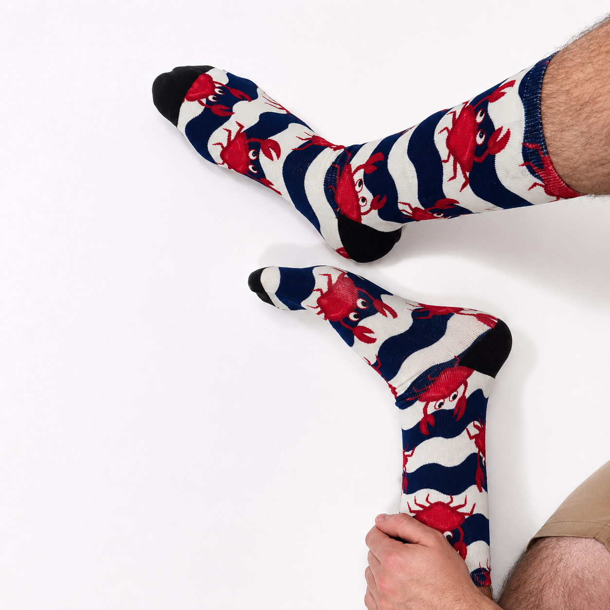 A pair of crew socks with a navy blue and white wavy stripe pattern and red cartoon crabs, worn on a person's legs against a plain white background.